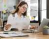 A small business owner reviewing website costs on a laptop with a simple budget chart or maintenance checklist.